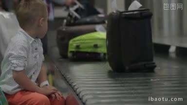 一个小男孩坐在<strong>机场</strong>的<strong>行李传送带</strong>旁，看着人们拿<strong>行李</strong>的慢镜头